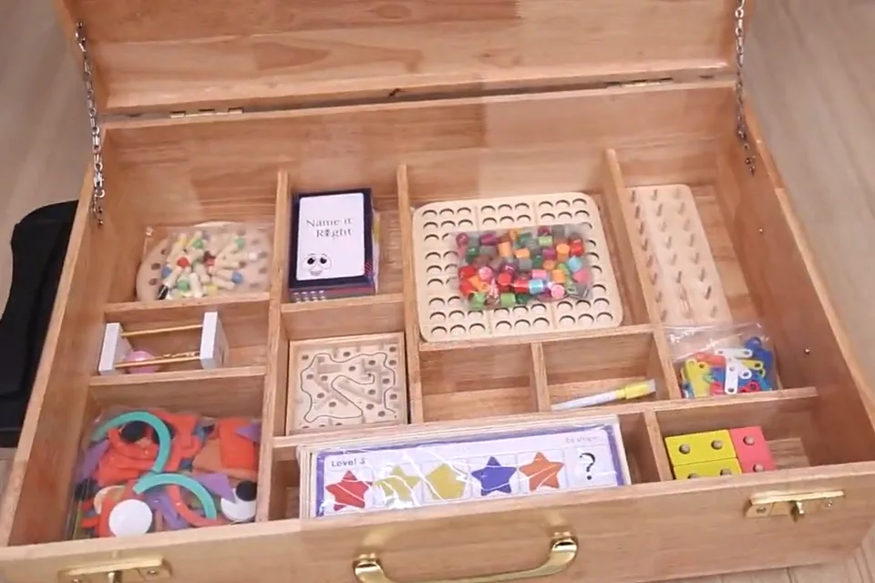 Open wooden Vayofit Wellness Kit case with compartments of puzzles, card games, peg boards and tangram pieces